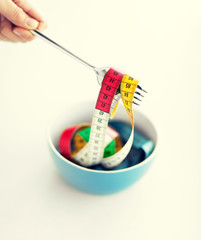 woman hand with fork, bowl and measuring tape