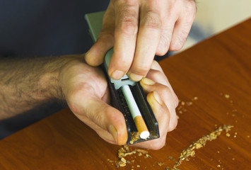 Fototapeta premium Man rolling cigarettes using fresh tobacco