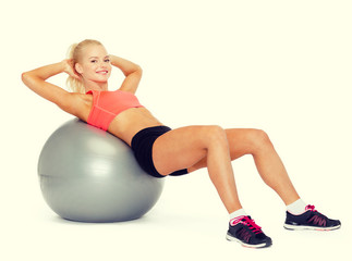 smiling sporty woman exercising on fitness ball