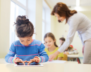 Obraz na płótnie Canvas little school girl with tablet pc over classroom