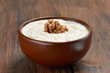Oatmeal porridge with walnuts in ceramic bowl