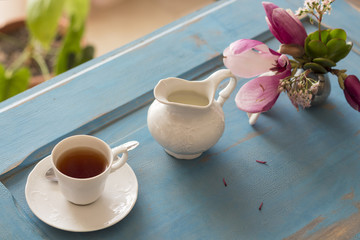 A tea cup and creamer on old wooden table. Top view.