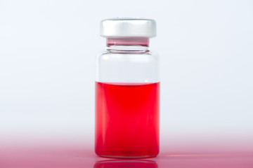 Injection vial of red liquid on red floor