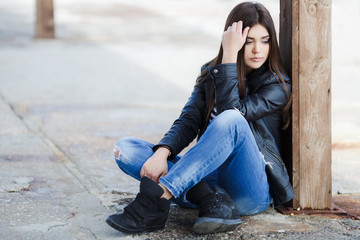 Portrait of a beautiful young woman sitting on the sidewalk.