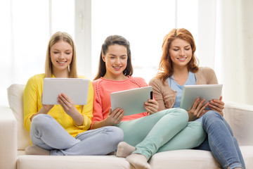 three smiling teenage girls with tablet pc at home