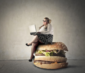Chubby woman sitting on a giant hamburger