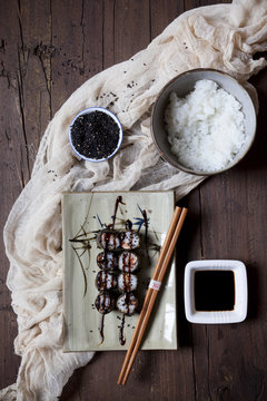 hosomaki sushi on plate with soy sauce and bowl of rice