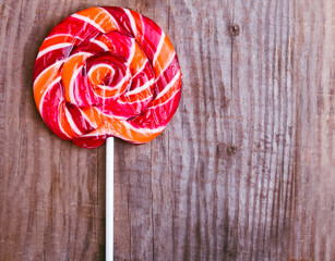 Red round lollipop on the wooden background