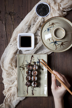 overhead shot of hands with chopstick taking sushi from plate
