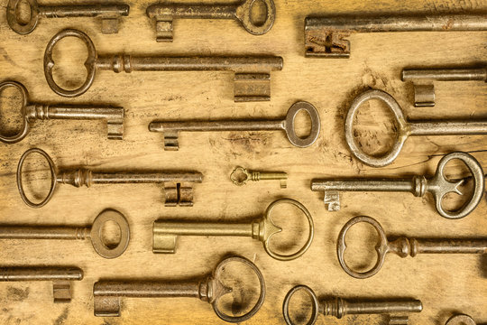 Different antique keys on a wooden background