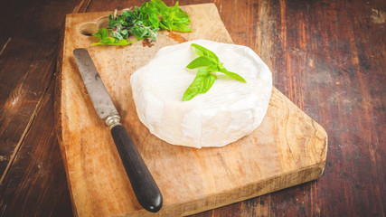 Smelly blue cheese on a wooden rustic table with knife and basil