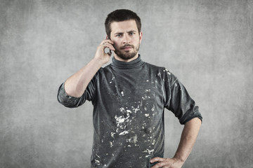 young man in working clothes talking on the phone