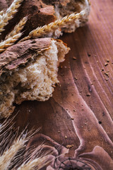 slice of bread with wheat ears on old wooden board