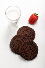 Chocolate shortbread biscuits and glass of milk on white wooden