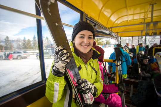 portrait of smiling woman riding in bus with skis