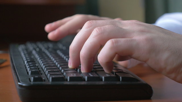4k - Close-up of a young man hands typing on a laptop keyboa