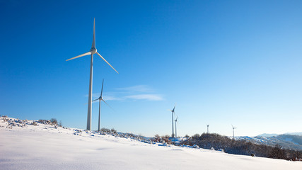 Fototapeta premium Typical windmill or aerogenerator of aeolian energy on snowy lan