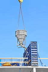 Crane lifting concrete mixer container against blue sky
