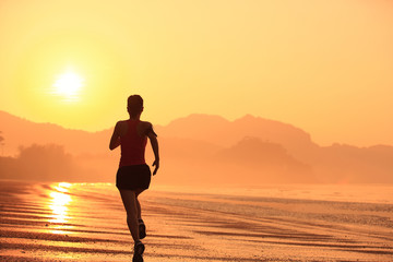 Fototapeta na wymiar young woman running on sunrise beach