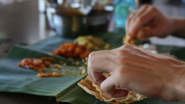 man eats rice  with flat cake from leaf  and focus is changes