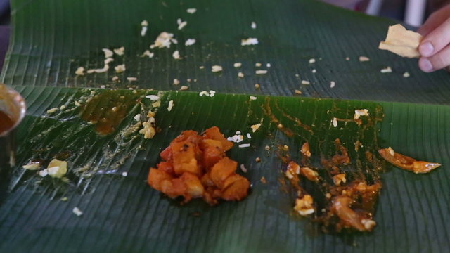 white man eats up Indian food and rolls up banana leaf