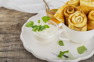 Thin golden pancakes hot rolled tubes in a white cup
