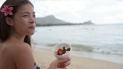 Acai bowl - woman eating healthy food on beach - Powered by Adobe