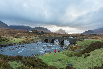 Man standing next to old Scottish Highland stone bridge