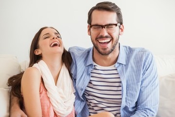 Young couple smiling at camera on couch