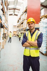 Warehouse worker smiling at camera with arms crossed