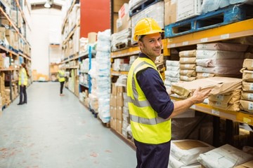 Warehouse worker taking package in the shelf