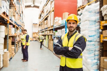 Smiling worker wearing yellow vest with arms crossed