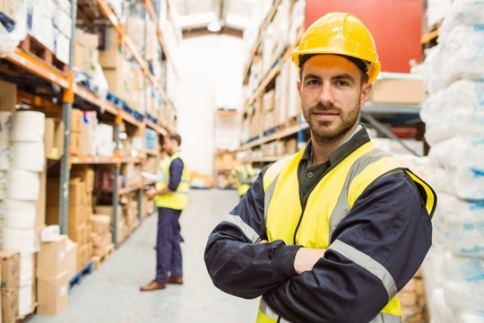 Smiling worker wearing yellow vest with arms crossed