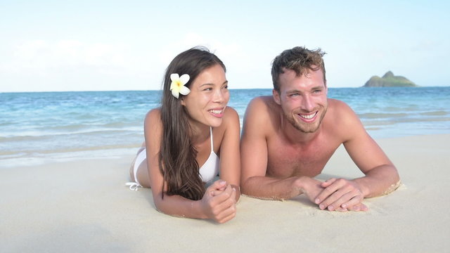 Hawaii vacation couple relaxing tanning on beach