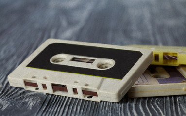 Retro audio cassette on the gray wooden background.