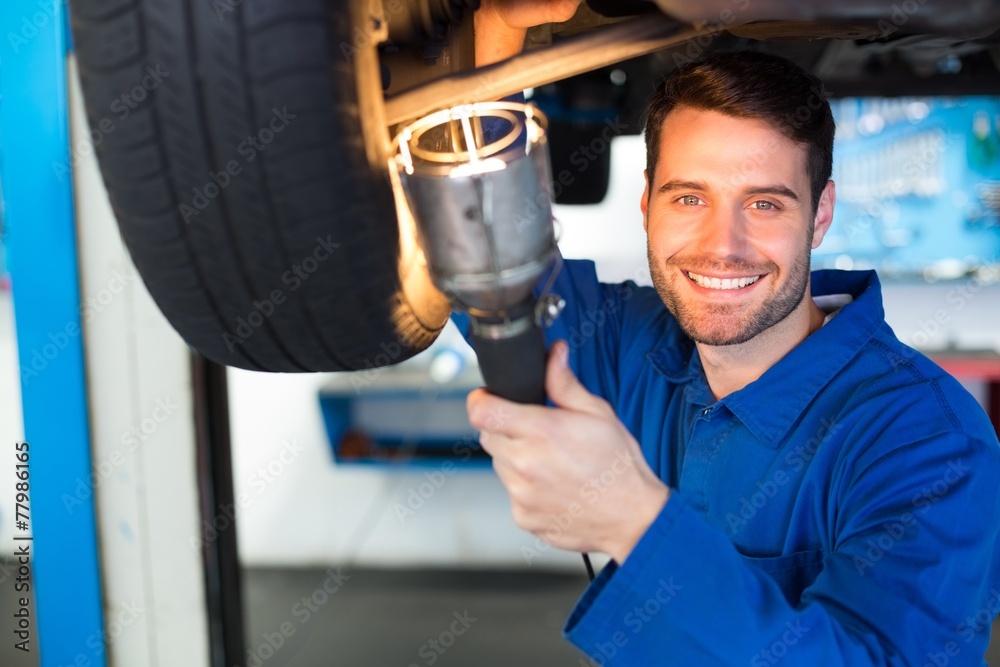 Poster Mechanic using torch to look under car