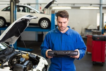 Mechanic examining under hood of car