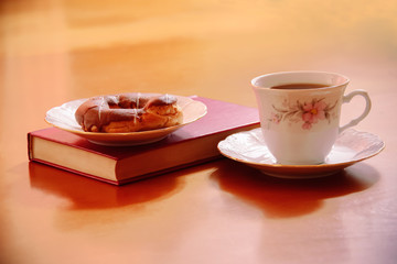 Tea cup with sweet cake and book