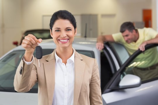 Smiling saleswoman showing a customer car key