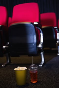 Empty rows of red seats with pop corn and drink on the floor