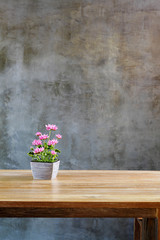 plastic flowers with pot on table in front of wall