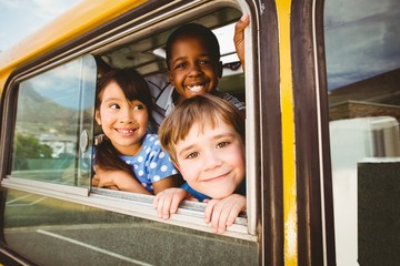 Cute pupils smiling at camera in the school bus