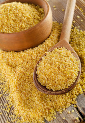 Bulgur in  wooden spoon on  a wooden background