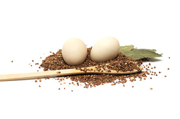 Buckwheat on a wooden spoon with eggs and egg laurel. Photo.