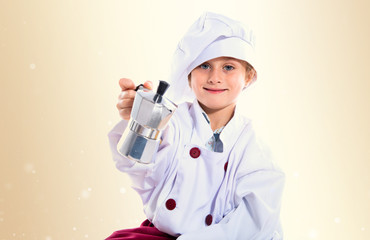 Blonde little girl dressed like chef holding coffee pot