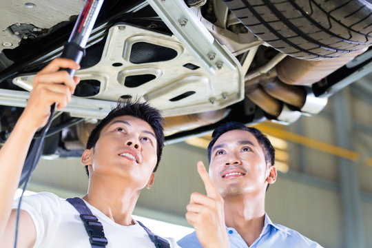 Car Mechanic And Customer In Asian Auto Workshop