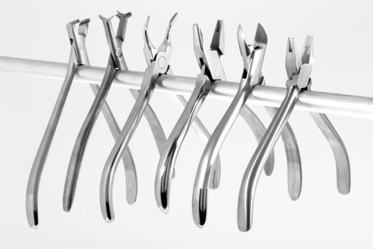 A set of six orthodontic pliers on a white background