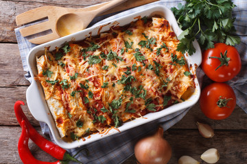 Mexican enchilada in a baking dish horizontal top view close-up