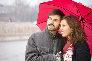 Woman and a bearded man under a red umbrella