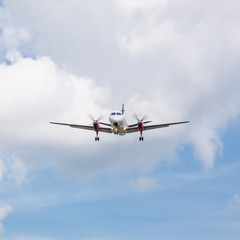Fototapeta na wymiar Propeller Plane Landing with Clouds